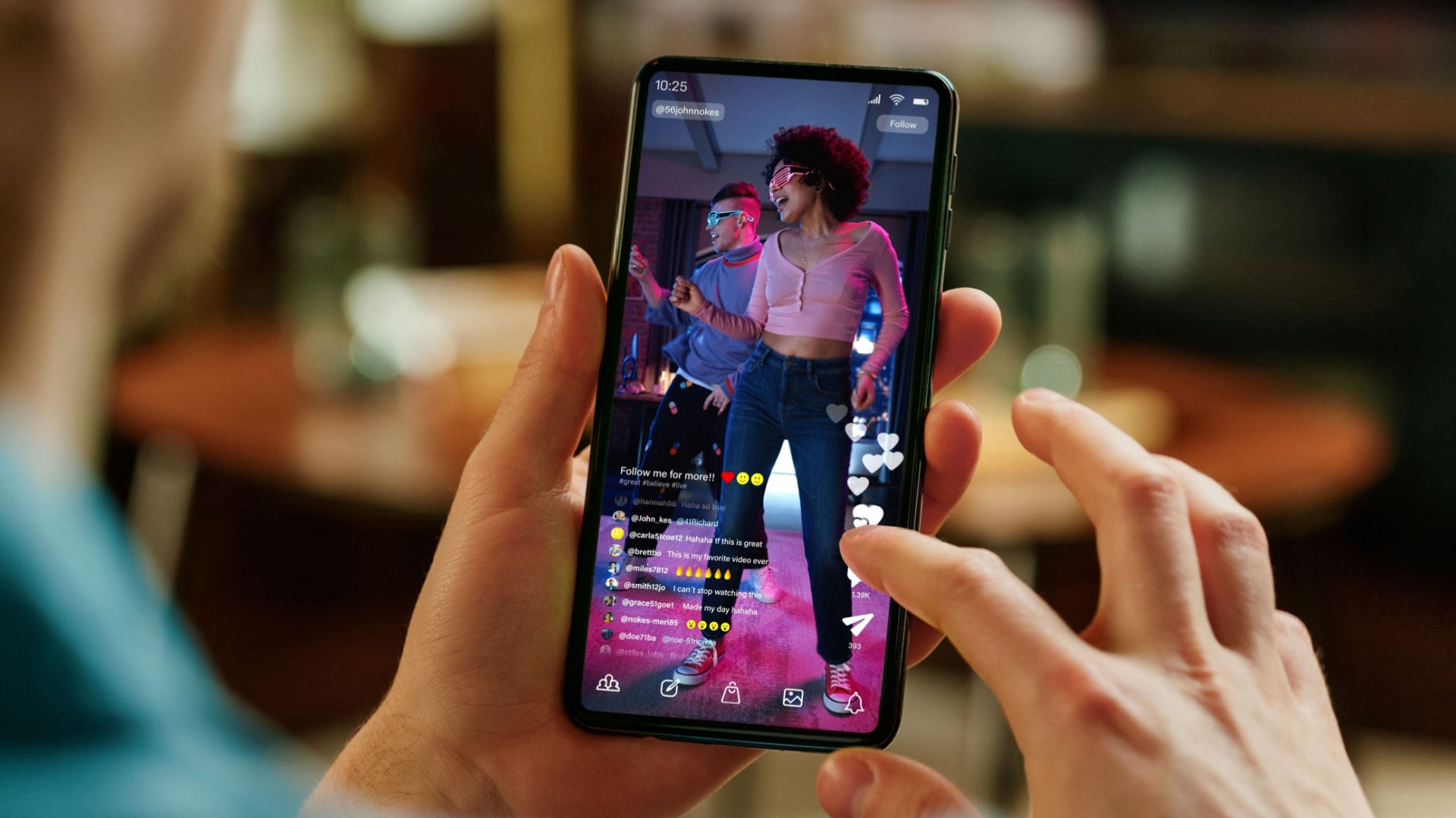 Close-up view of a person holding a smartphone streaming a live video of two dancers, showcasing modern interactive video content trends on social media platforms