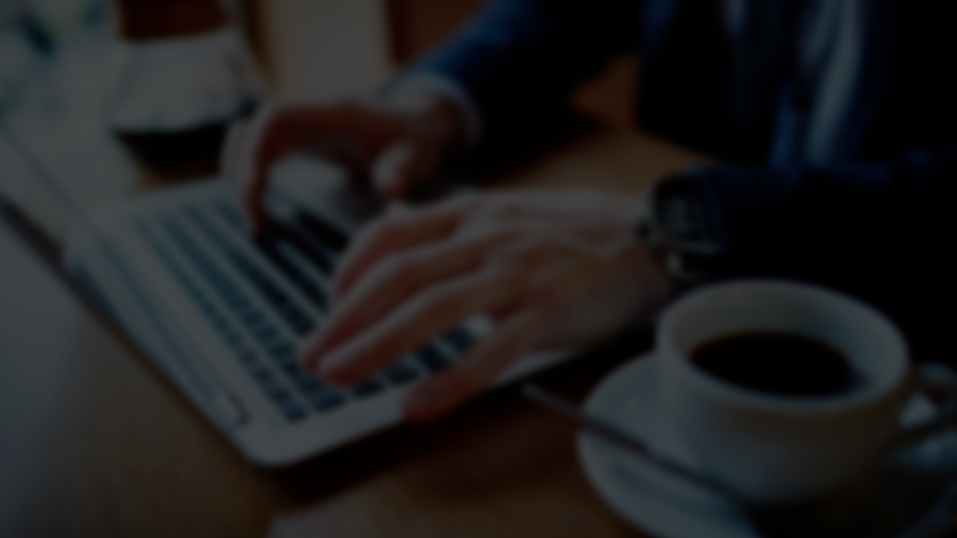 A person writing a blog post for a website is working on their laptop. They have a cup of coffee beside them and a comfortable working environment.
